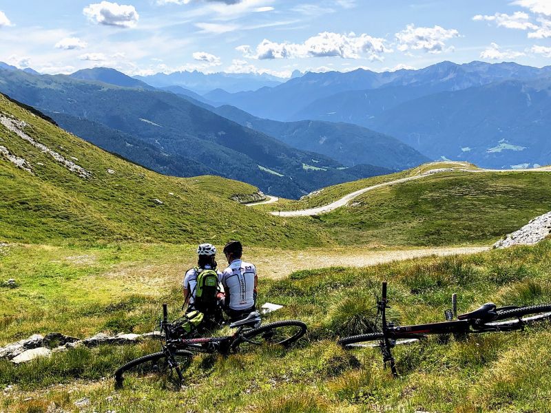 Zwei Mountainbiker machen Pause am Sandjöchl mit Blick nach Südtirol
